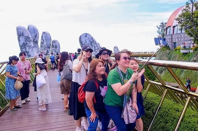 国际游客兴奋地在岘港市巴拿山太阳世界旅游区的金桥上打卡。（图：陈黎霖）