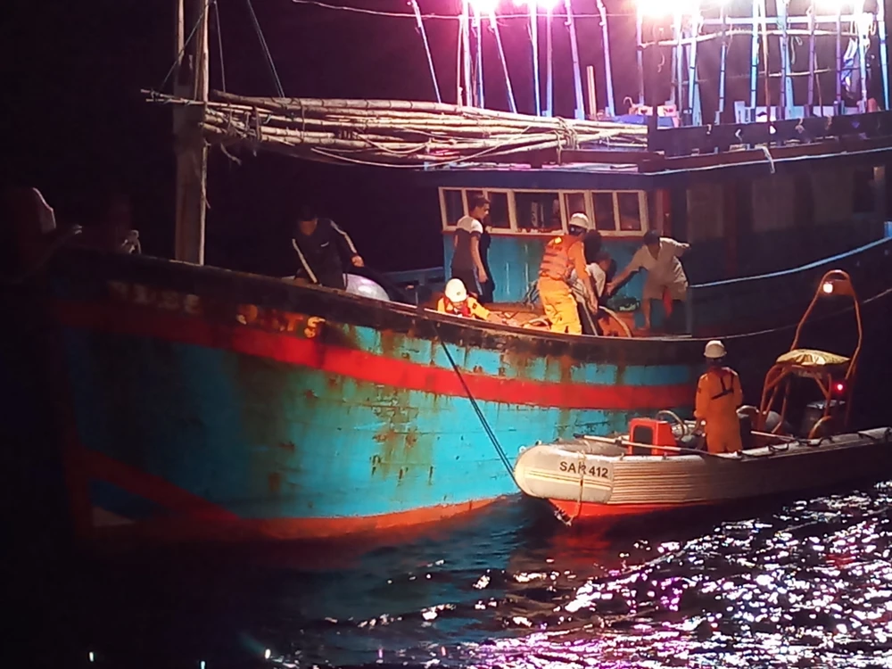 Các nhân viên cứu nạn đưa ngư dân Huỳnh Văn Cương sang tàu cứu nạn bằng xuồng cao su 