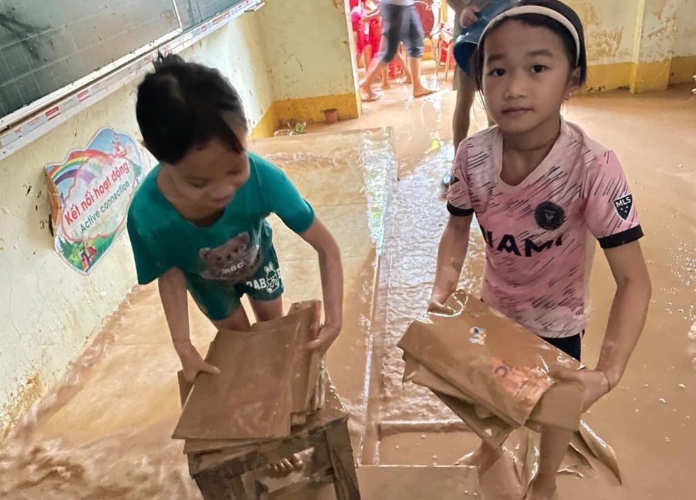Học sinh điểm trường Tà Sỏi thuộc Trường tiểu học Châu Hạnh 2 (huyện Quỳ Châu, tỉnh Nghệ An) dọn sách vở trong đống bùn đất