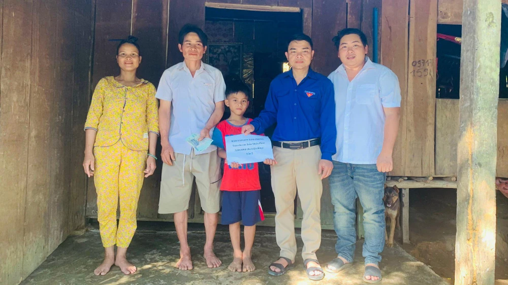 Thầy Kha (áo trắng) cùng Bí thư đoàn xã Trà Giác, trao tặng quà của bạn đọc Báo SGGP đến bé Phan. Ảnh: QUỲNH LÂM