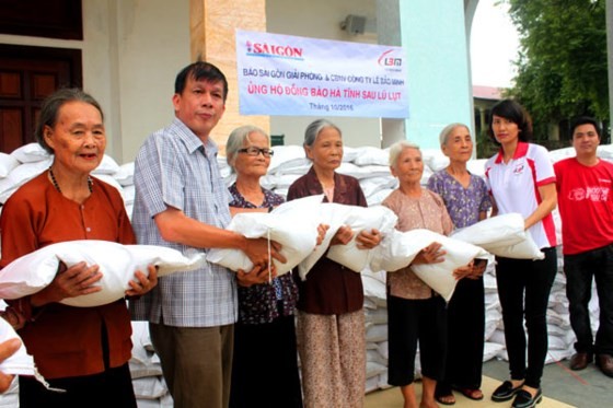 A representative of Sai Gon Giai Phong Newspaper (2nd, L) gives elderly people rice bags in Huong Khe district, the north central province of Ha Tinh where was ravaged in a flooding in October last year (Photo: SGGP)