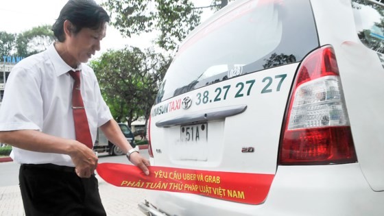 A driver removes the red banner protesting against Uber and Grab in HCMC street (Photo: SGGP)