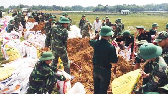 Military soldiers help residents fortify embankments in Quoc Oai district, Hanoi (Photo: SGGP)