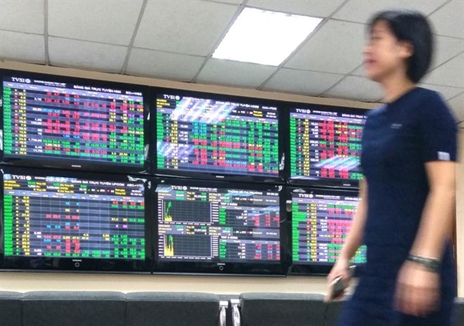 An investor passes by trading screens at Tan Viet Securities Company in Hanoi. (Photo: VNA)