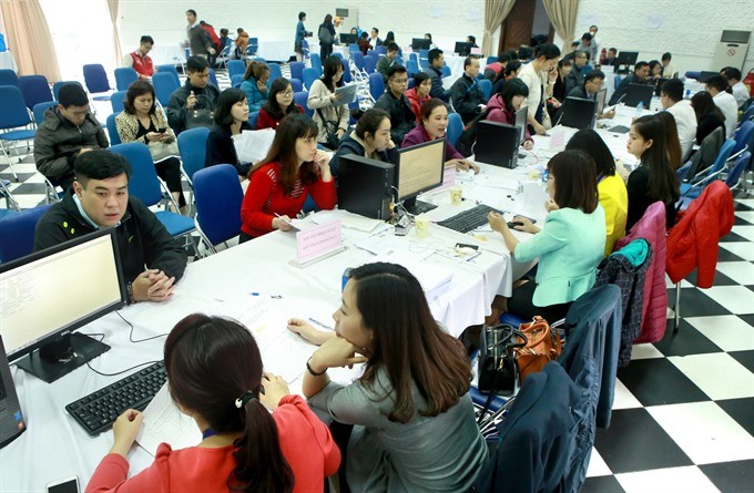 Tax officials (on the right side of the tables) receive personal income tax finalisation documents from Hanoi residents. The Vietnamese Government aims to considerably increase the number of administrative procedures processed via electronic systems in th
