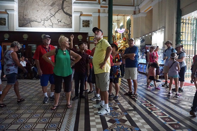 A tour guide with a group of tourists at the Central Post Office in HCM City. Photo: VNS