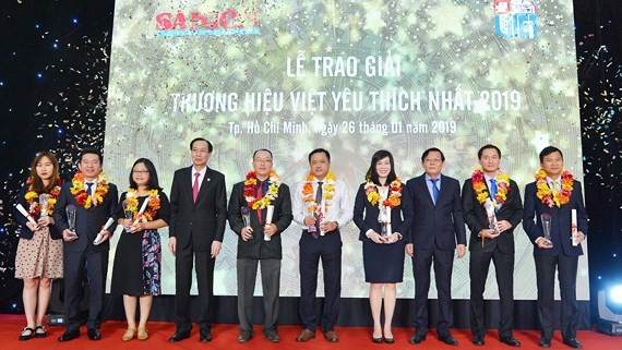 Standing Deputy Chairman of the Ho Chi Minh City People’s Committee Le Thanh Liem and SGGP’s editor in chief Nguyen Tan Phong give the Most Favorite Vietnamese Brands Awards to enterprises. (Photo: SGGP)