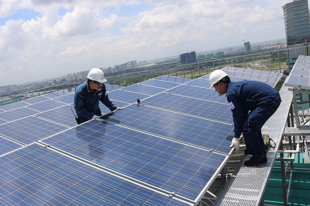 Workers install solar panels on the roof of a building. (Photo: SGGP)