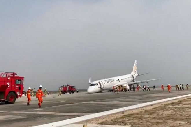 A passenger records the scene on her phone as firefighters attend to the scene after Myanmar Airlines flight UB103 landed without a front wheel at Mandalay International Airport (Photo: REUTERS)