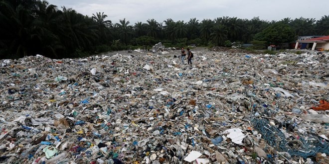 People walk through plastic waste piled outside an illegal recycling factory in Jenjarom in Kuala Langat district, Malaysia. (Photo: Reuters)
