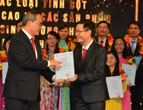Secretary Nguyen Thien Nhan (L) gives the awards to the work ‘Study of the technological process of producing high resistant starches and low-sugar food produ from Vietnam's foods cts for obese and diabetic patients' (Photo: SGGP)