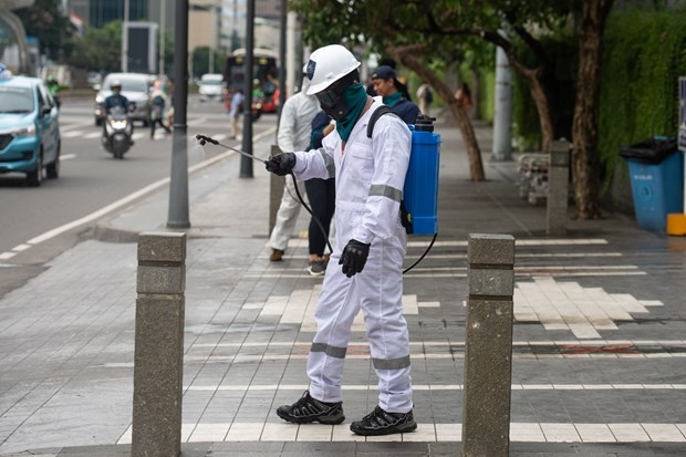 A worker fumigates the pavement in Jakarta, Indonesia, on March 19 in a bid to prevent the spread of the novel coronavirus (Photo: Xinhua/VNA)