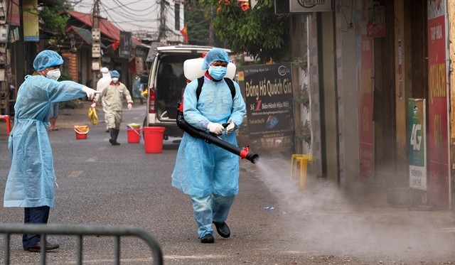 Medical workers spray steriliser in Ha Loi Village where two COVID-19 patients live (Photo: VNA/VNS)
