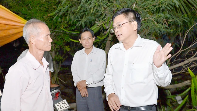 Phó Chủ tịch UBND huyện Bình Chánh Nguyễn Văn Tài (bìa phải) trực tiếp đến nhà ông Võ Văn Kim vào buổi tối để vận động việc giải phóng mặt bằng xây dựng đường cao tốc Bến Lức - Long Thành Ảnh: VIỆT DŨNG