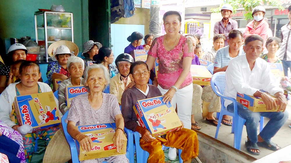 Bà Tâm (đứng) trao quà tặng người nghèo