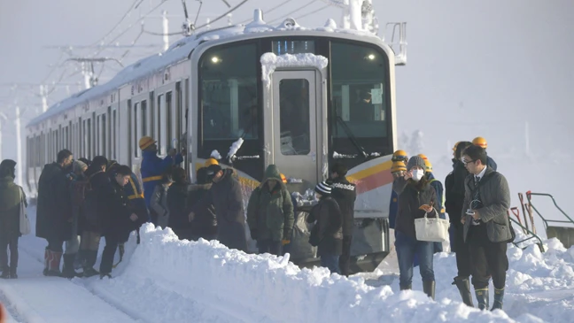 Hành khách ra khỏi xe lửa sáng 12-1-2018 sau khi phải qua đêm trên đoàn xe lửa bị mắc kẹt do tuyết rơi dày ở TP Sanjo, tỉnh Niigata, Nhật Bản. Ảnh: KYODO
