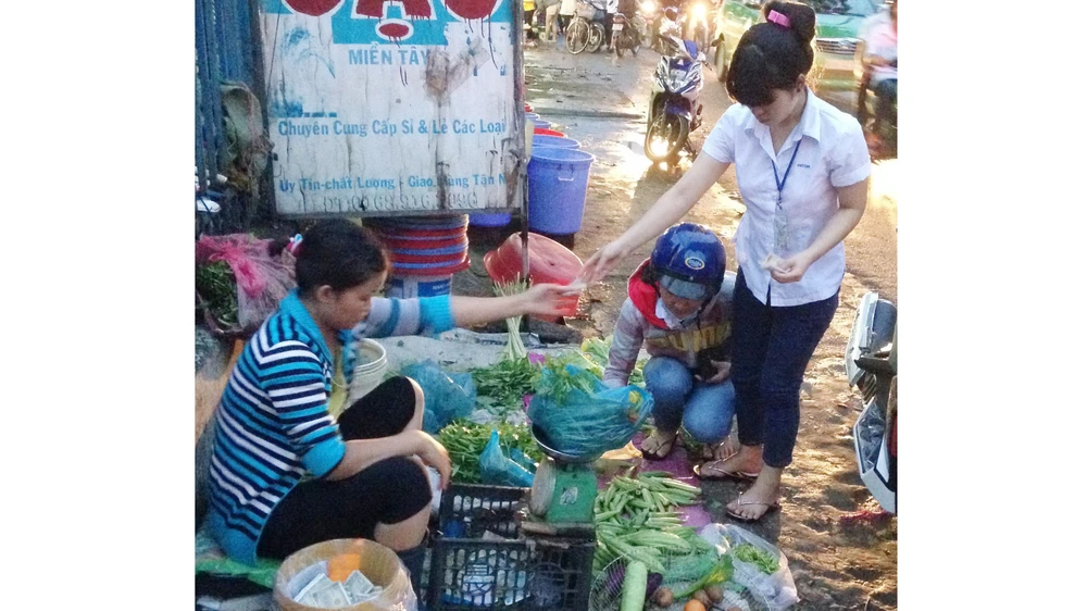 Công nhân tan ca chọn mua rau tại chợ tự phát trên đường Lê Văn Chí, quận Thủ Đức. Ảnh: HẢI THU