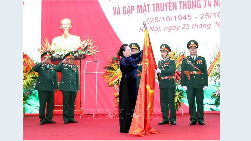 Chủ tịch Quốc hội Nguyễn Thị Kim Ngân gắn Huy hiệu Anh hùng LLVT lên lá cờ truyền thống của Tổng cục II. Ảnh: TTXVN