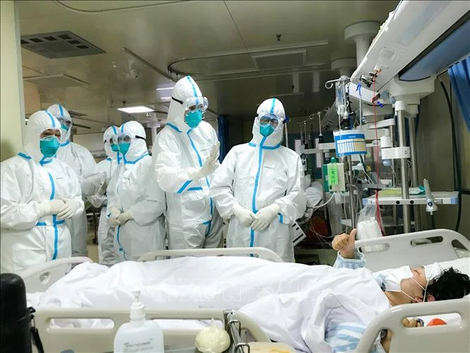Nhóm bác sĩ bệnh viện Trường đại học quân y số 2 kiểm tra sức khỏe một bệnh nhân tại bệnh viện Hankou ở Vũ Hán, tỉnh Hồ Bắc ngày 27-1. Ảnh: THX/TTXVN