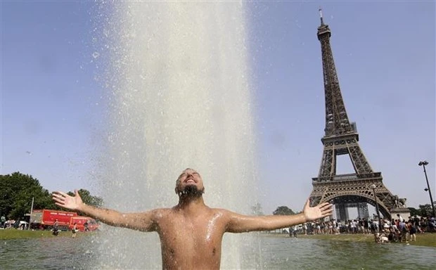 Người dân giải nhiệt tránh nắng nóng tại một đài phun nước ở Paris (Pháp), ngày 18-6-2022. Ảnh: AFP/TTXVN