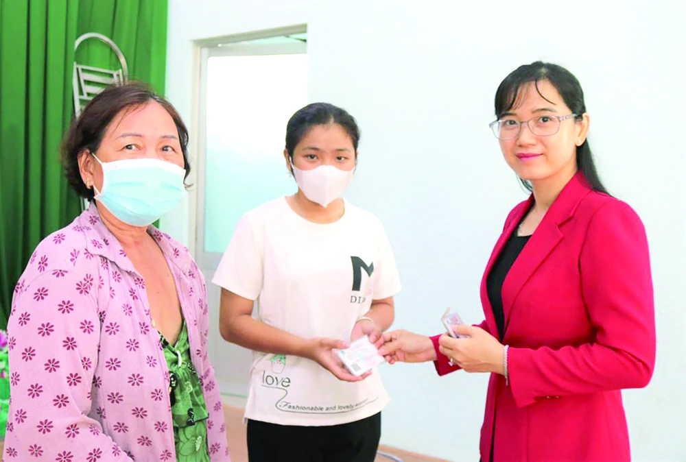 Bà Nguyễn Thị Mỹ Duyên - Phó Trưởng phòng Kế toán Công ty TNHH MTV XSKT Đồng Tháp trao tặng thẻ bảo hiểm y tế cho người dân