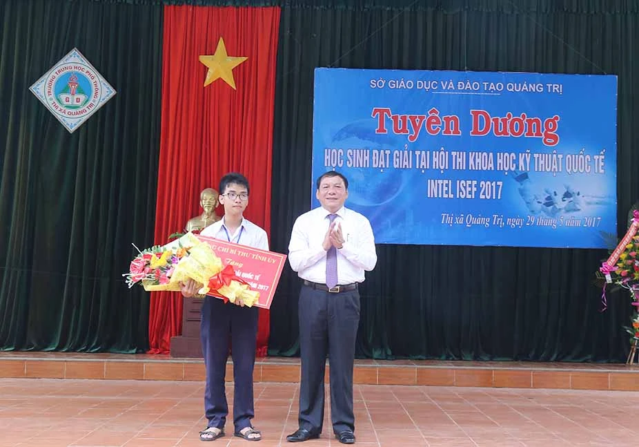Ông Nguyễn Văn Hùng, Bí thư tỉnh uỷ Quảng Trị tặng hoa và tiền thưởng cho Phạm Huy- tác giả của sản phẩm Cánh tay robot cho người khuyết tật.
