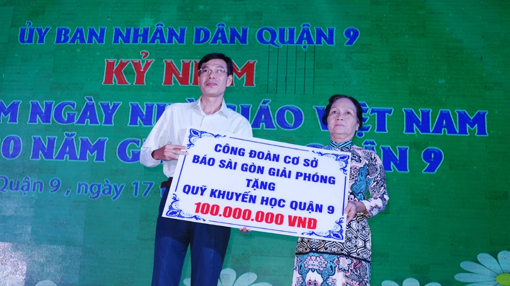 Ông Phạm Trường, Phó Tổng Biên tập Báo Sài Gòn Giải Phóng, trao bảng tượng trưng ủng hộ Quỹ Khuyến học Quận 9 (TPHCM) 100 triệu đồng. Ảnh: TRỌNG NGHI