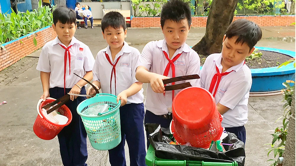 Học sinh Trường Tiểu học Lý Nhân Tông, quận 8 (TPHCM) thu gom rác ở trường, thực hiện phân loại rác tại nguồn Ảnh: THÀNH TRÍ