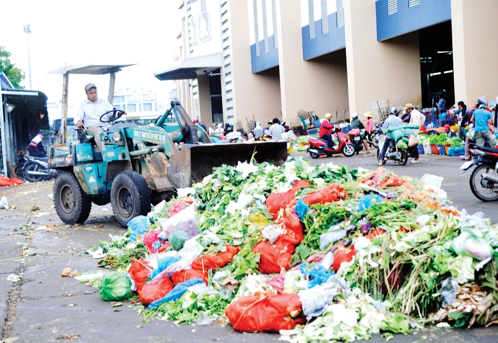 Thu dọn rác tại một bãi tập kết rác ở chợ Bình Điền Ảnh: THÀNH TRÍ