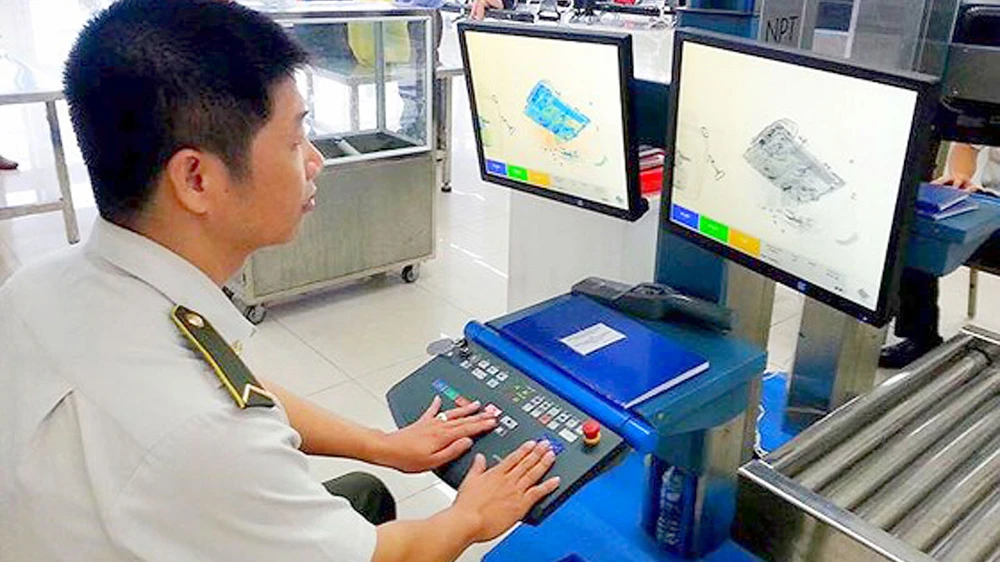 Nhân viên an ninh kiểm tra hành lý qua máy soi tại sân bay Nội Bài