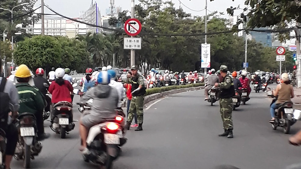 Các nhân viên bảo vệ của cao ốc gần cầu Sài Gòn ra đường phân luồng cho xe máy lưu thông qua làn đường dành cho ô tô Ảnh: ĐOÀN HIỆP