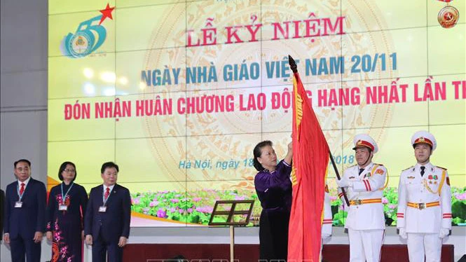Chủ tịch Quốc hội Nguyễn Thị Kim Ngân gắn Huân chương Lao động hạng Nhất lần thứ hai lên lá cờ truyền thống của Học viện Tài chính. Ảnh: TTXVN