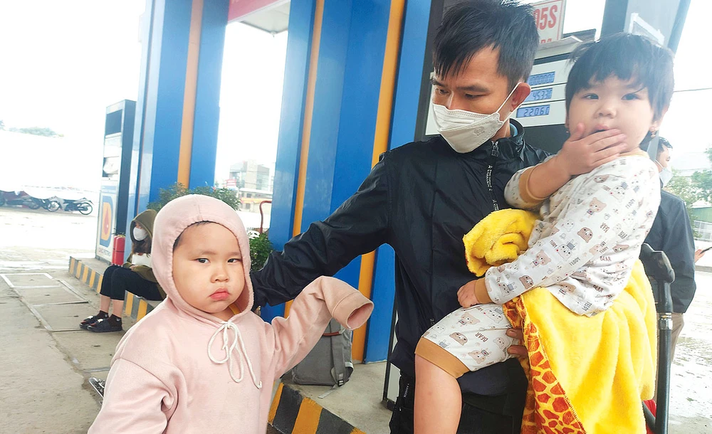 Anh Nguyễn Sửu cùng con đứng chờ xe khách vào Đồng Nai ngày 27-1 tại thị trấn Nghèn, huyện Can Lộc, Hà Tĩnh