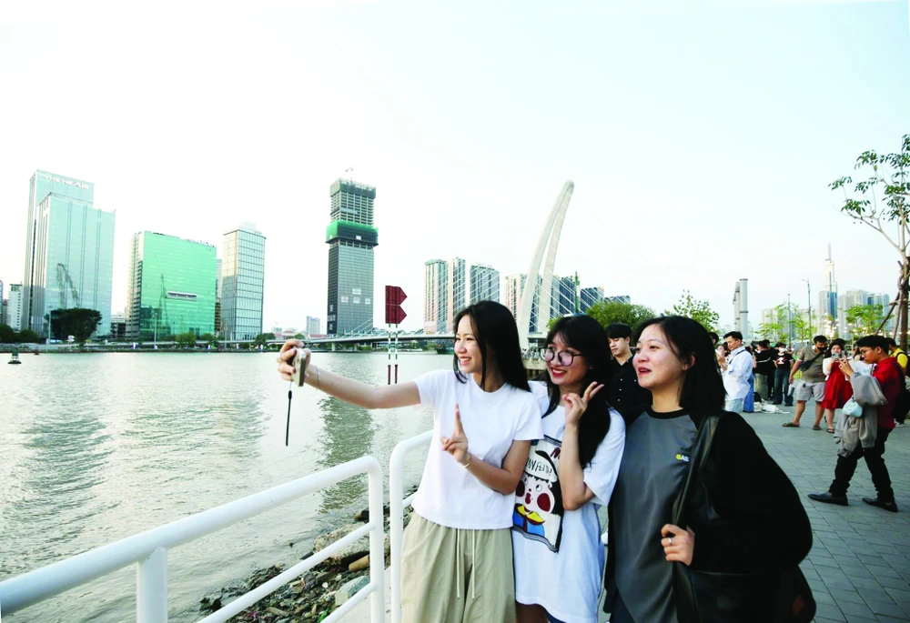 Các bạn trẻ chụp ảnh lưu niệm bên bờ sông Sài Gòn. Ảnh: DŨNG PHƯƠNG