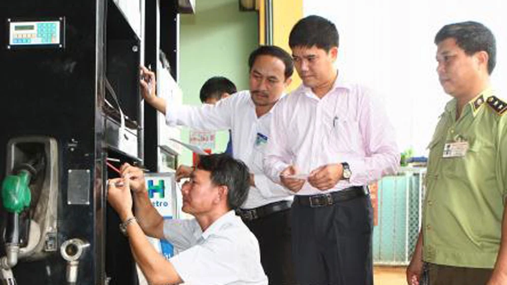 Đoàn liên ngành tỉnh Đắk Lắk thực hiện dán tem trụ bơm xăng dầu ở huyện Cư Mgar. Ảnh: TTXVN