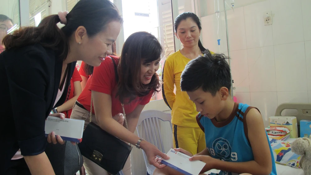 Bà Trần Thị Kim, Phó Giám đốc BIDV chi nhánh Nam Kỳ Khởi Nghĩa và đại diện báo SGGP tặng quà cho bệnh nhi tại Khoa ung bướu huyết học bệnh viện Nhi đồng 2 TPHCM