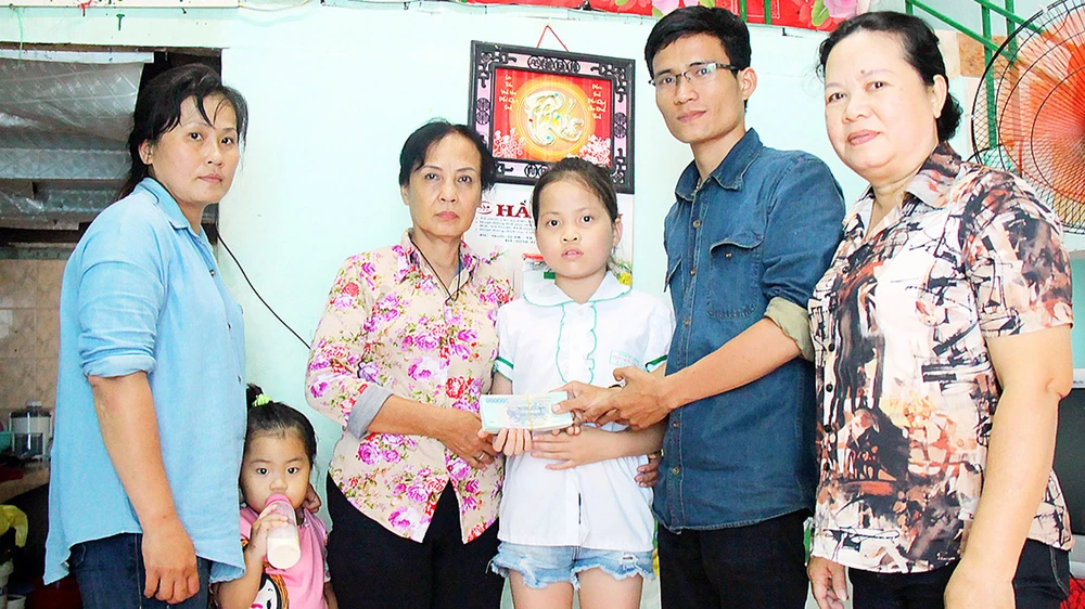 Đại diện Báo SGGP trao 25,5 triệu đồng do bạn đọc báo ủng hộ gia đình cháu Lê Thị Bảo Linh. Ảnh: NGỌC OAI