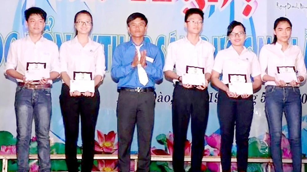 Trần Hữu Việt (thứ 3 từ trái sang) tặng học bổng cho học sinh nghèo của địa phương