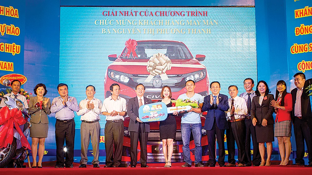 Ông Lê Hữu Hoàng, Chủ tịch HĐTV Công ty Yến sào Khánh Hòa (thứ 6 từ phải sang) trao giải nhất của chương trình là 1 chiếc xe ô tô Civic cho khách hàng Nguyễn Thị Phương Thanh (Buôn Ma Thuột, Đăk Lăk)