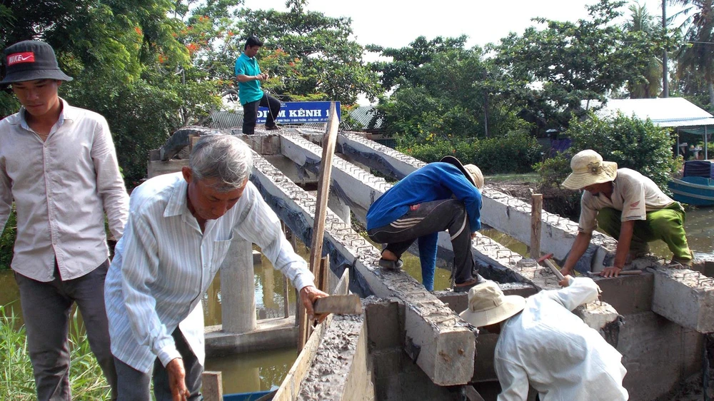 Người dân tình nguyện ở ấp Minh Kiên A đang cạy ván cốp pha, đổ móng cầu Kênh 10 