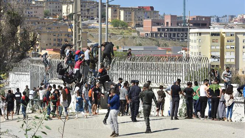 Người di cư trèo qua hàng rào biên giới tại Fnideq, Maroc, để sang vùng Ceuta của Tây Ban Nha ngày 18-5-2021. Ảnh: THX