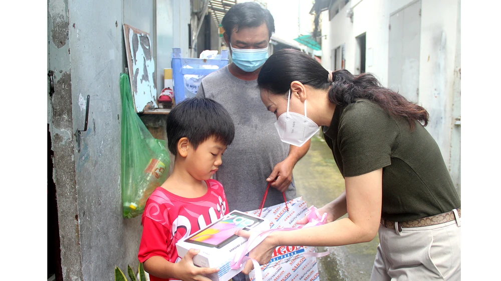 Đại diện Báo SGGP trao tặng máy tính bảng và tập vở mới cho bé Nguyễn Anh Tấn, con anh Nguyễn Văn Bình (quận Gò Vấp)