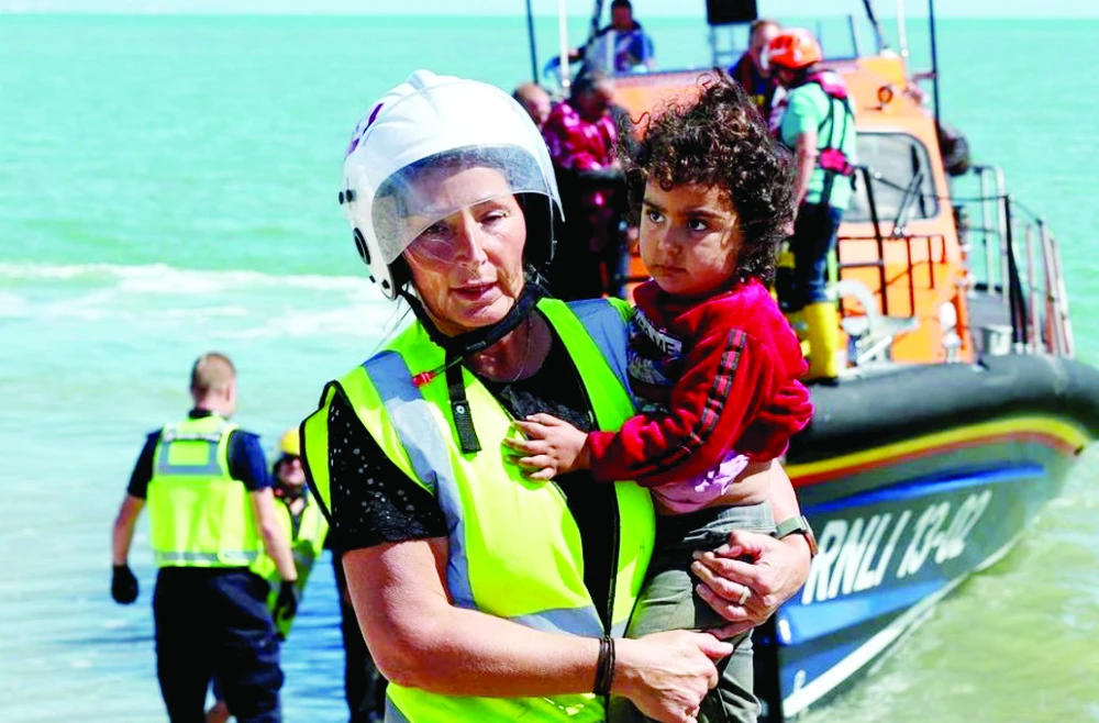 Nhân viên cứu hộ bồng một em bé di cư đến Dungeness, Anh, vào tháng 8-2023
