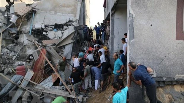 Người dân tìm kiếm người bị mắc kẹt trong những đống đổ nát sau vụ không kích của Israel tại Khan Younis, Dải Gaza, ngày 11-10-2023