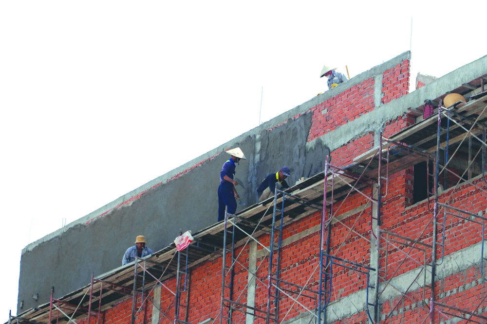 Công nhân xây dựng làm việc trên tầng cao công trình xây dựng nhà ở trên đường Cộng Hòa (quận Tân Bình, TPHCM) thiếu trang bị bảo hộ lao động. Ảnh: NGÔ BÌNH