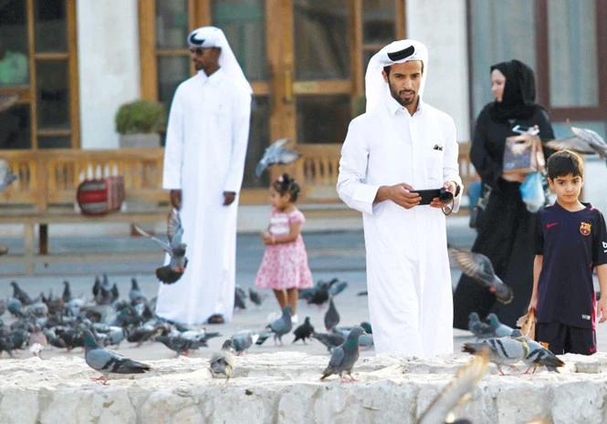Khách bộ hành đi bên bầy bồ câu ở chợ Souq Waqif, Qatar