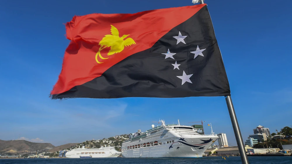 The national flag of Papua New Guinea flies in front of boats berthed in Port Moresby. China's Huawei has won a bid to build the country's telecommunications network. © Getty Images