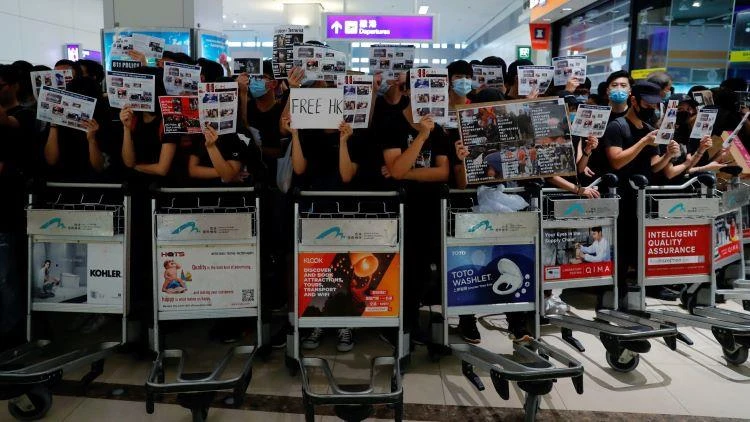 Anti-extradition bill protesters use trolleys to stop passengers from entering the security gates during a mass demonstration at Hong Kong International Airport on Aug.13. © Reuters