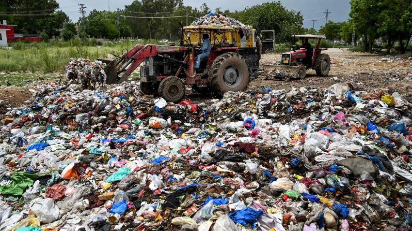Workers load garbage into a dump truck at a trash dump teeming with plastic bags in Islamabad. © AFP/Jiji