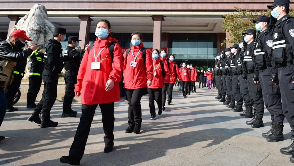 Policemen salute medical workers from Mongolia in Wuhan, Hubei Province on March 18. The workers had been brought to the province to help contain the coronavirus outbreak. © AP